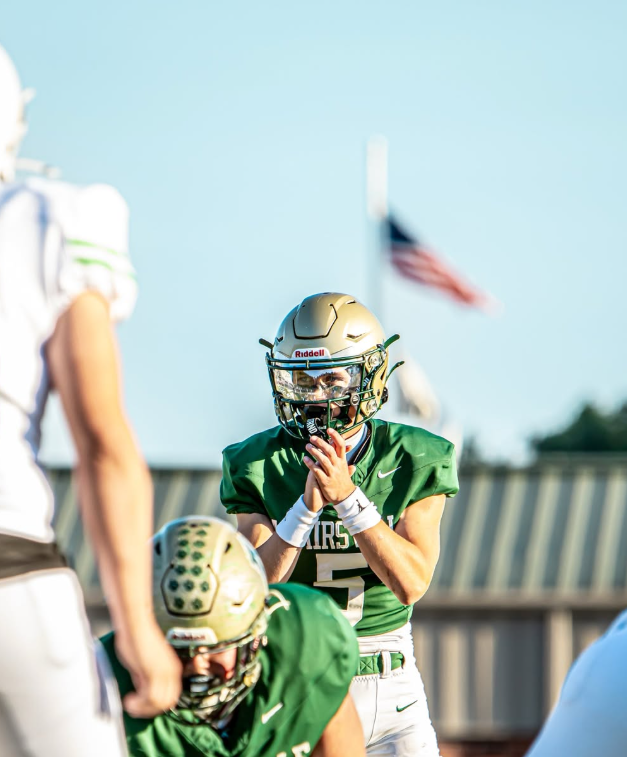 Adairsville football players running onto the field under stadium lights